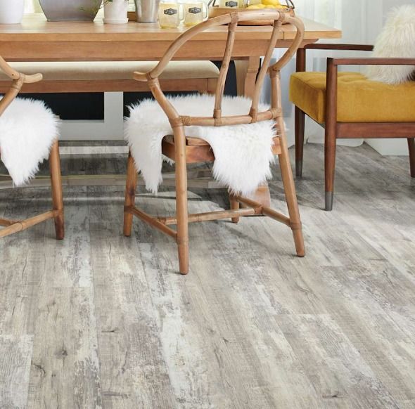 Dining room with light wood flooring, table, chairs with sheepskin, and a yellow armchair.