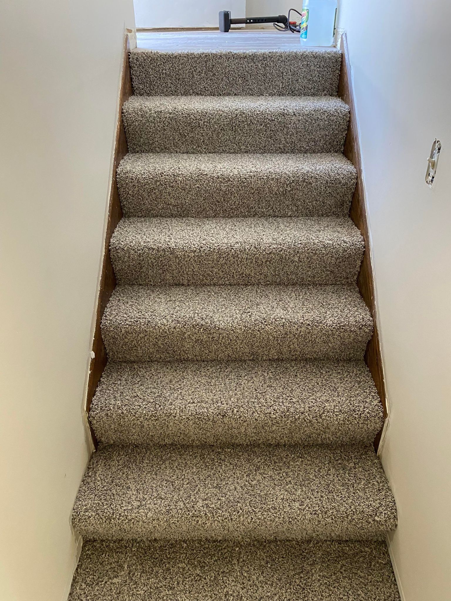 Carpeted stairs with brown wood sides and light-colored walls.