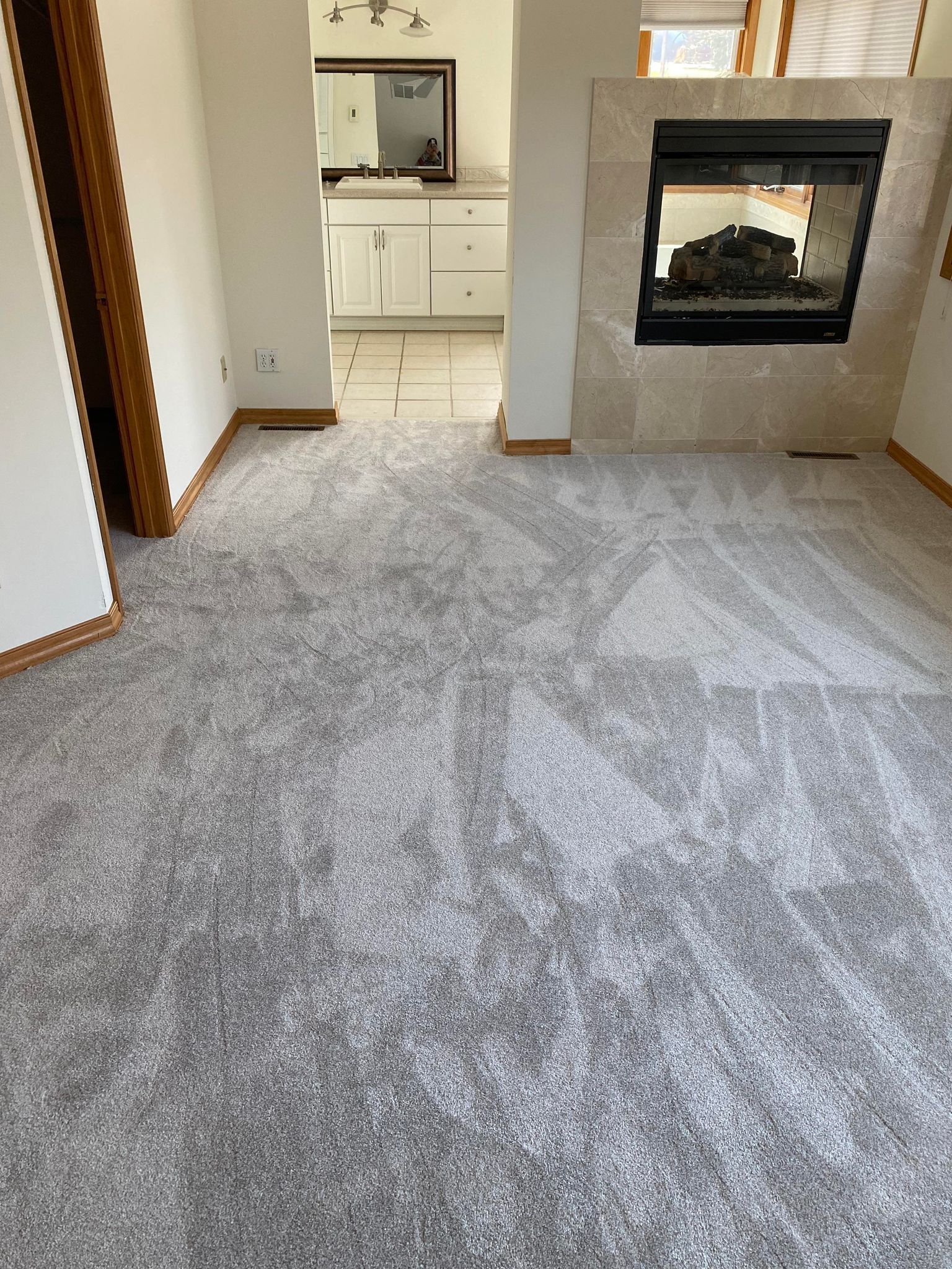 Gray carpeted room with fireplace and doorway leading to a bathroom.