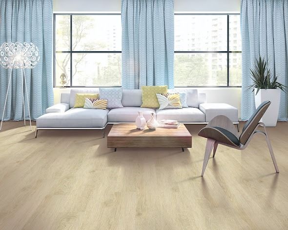Living room with pale wood flooring, a white sofa, and blue curtains.