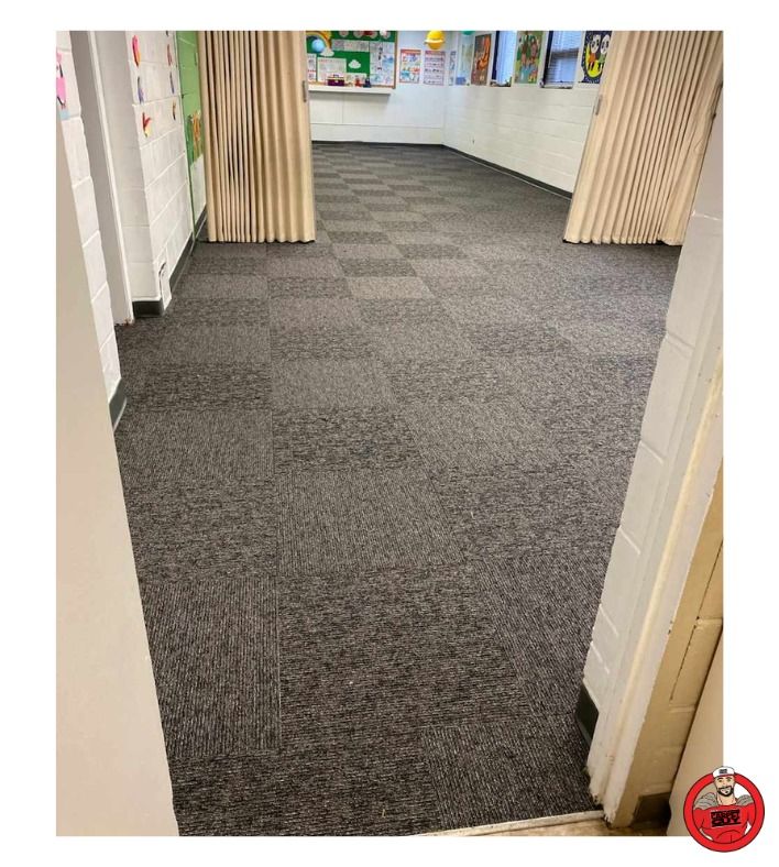 Room with gray square-tiled carpet, beige curtains, and white walls.
