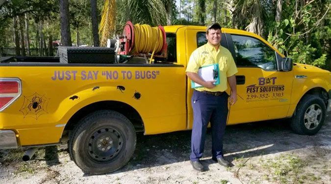 A man is standing in front of a yellow truck that says `` just say no to bugs ''.