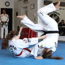 A woman in a taekwondo uniform is doing a handstand.