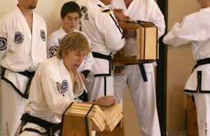 A group of people in karate uniforms are standing around a wooden box.