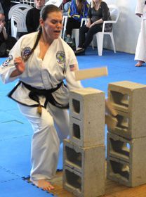 A woman in a karate uniform is breaking concrete blocks.