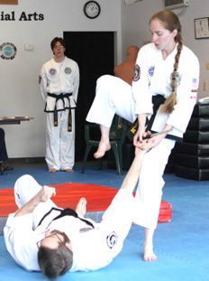 A man is laying on the ground while a woman lifts him up.