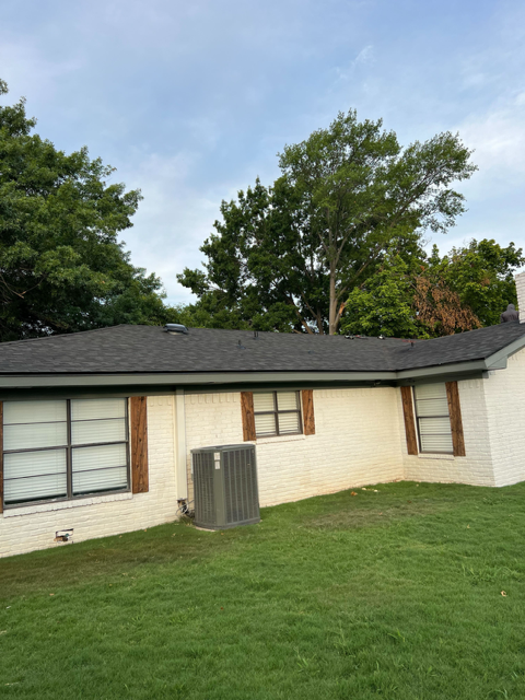 A white house with a black roof and a gray air conditioner