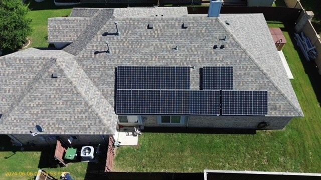 An aerial view of a house with solar panels on the roof.