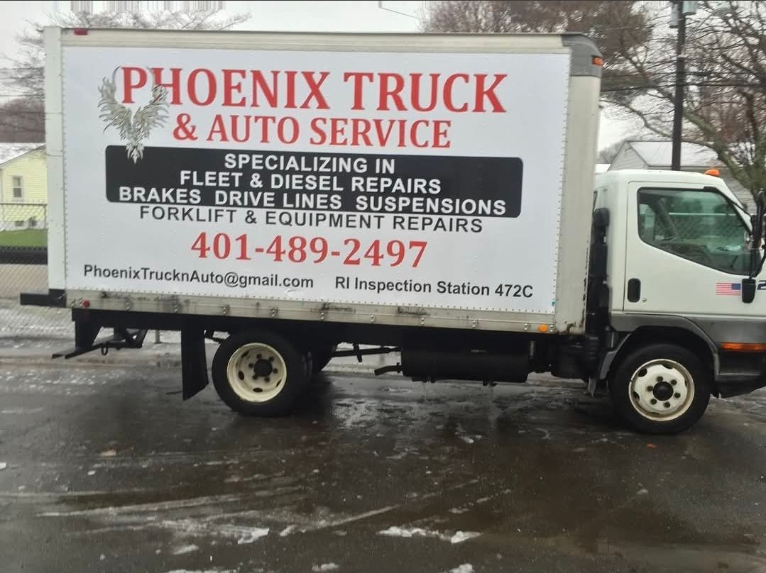 White Phoenix Truck & Auto Service box truck parked on a wet street with company signage.