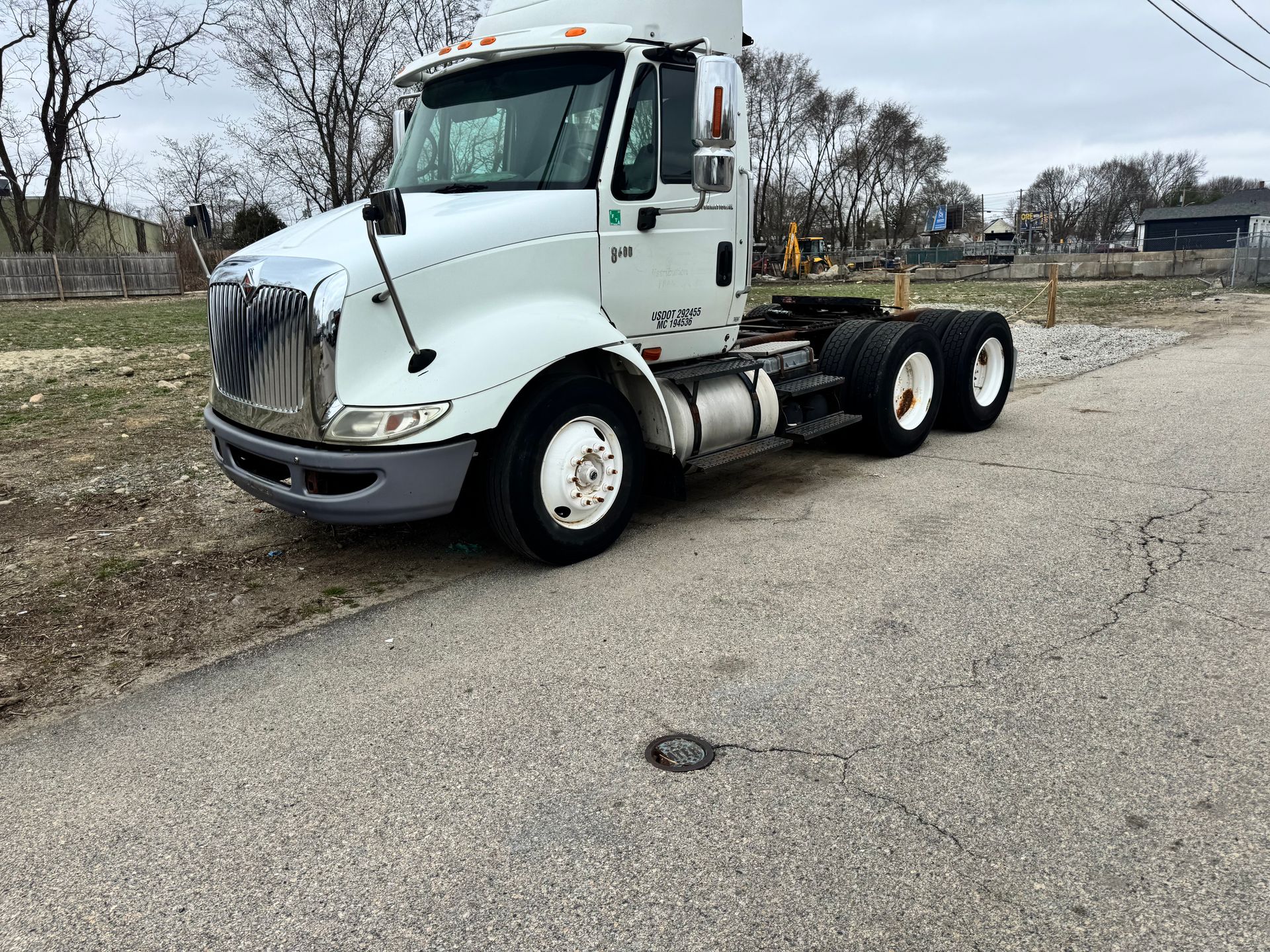 White semi-truck cab parked on a roadside in a sparse industrial area