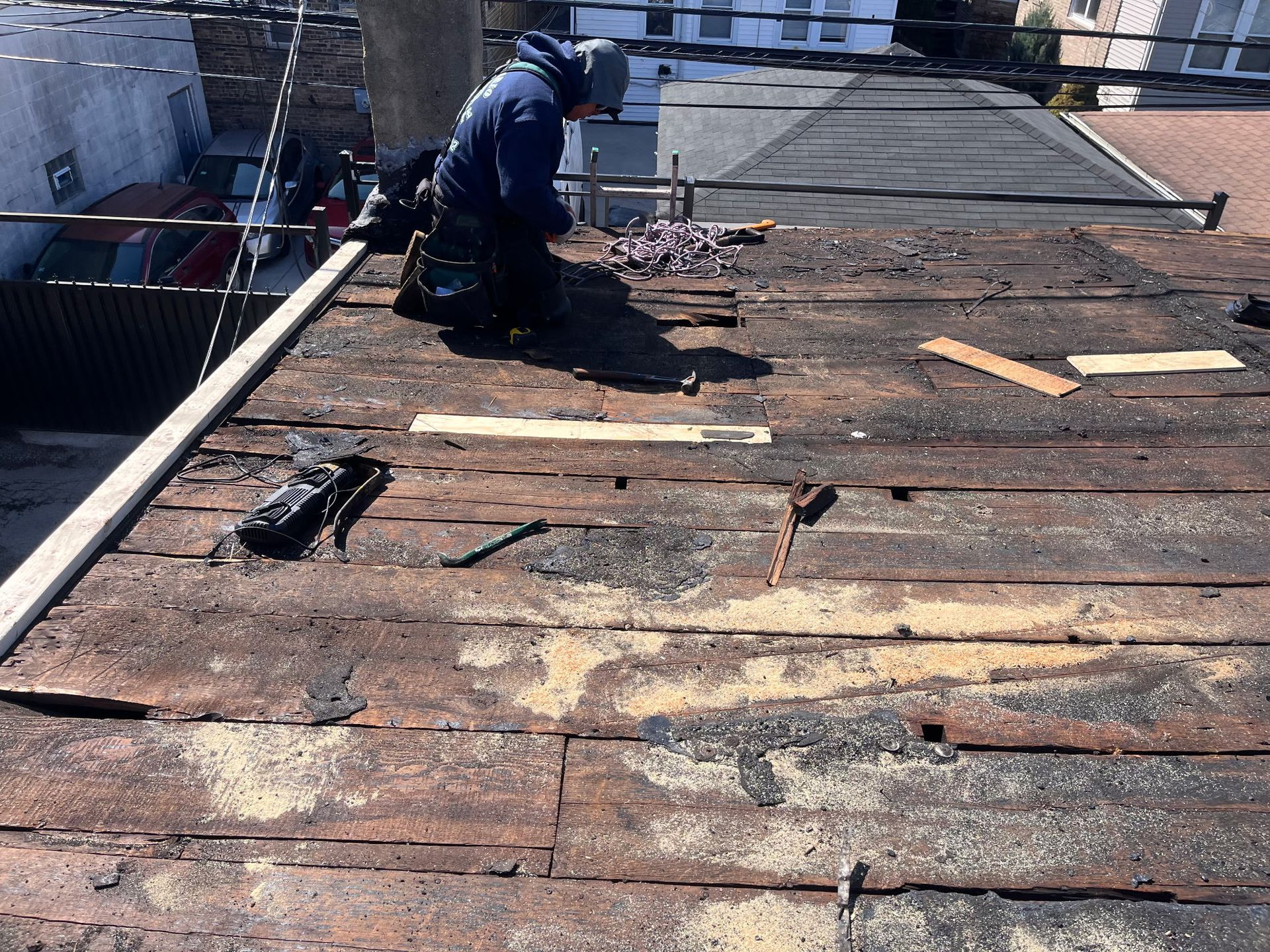 A worker on a weathered flat roof, surrounded by tools and debris, possibly repairing it.