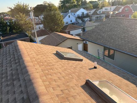 View of rooftops in a residential area, including a roof with two skylights, on a sunny day.