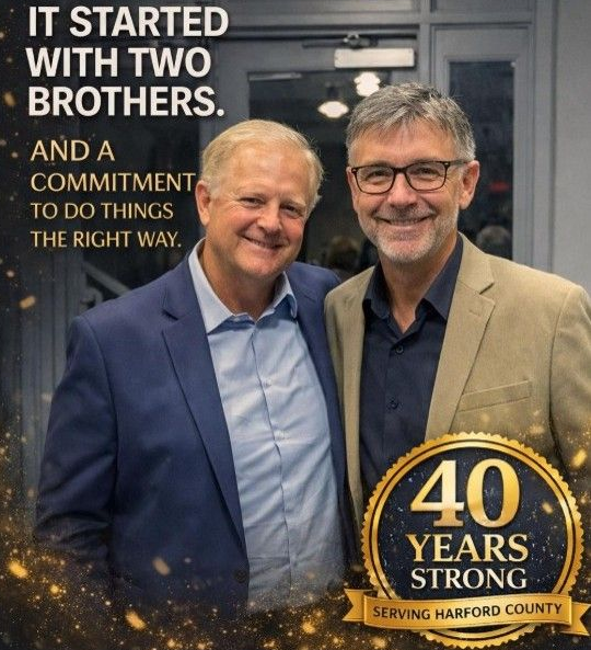 Two smiling men in suits pose with a “40 Years Strong” sign and the text “It started with two brothers”