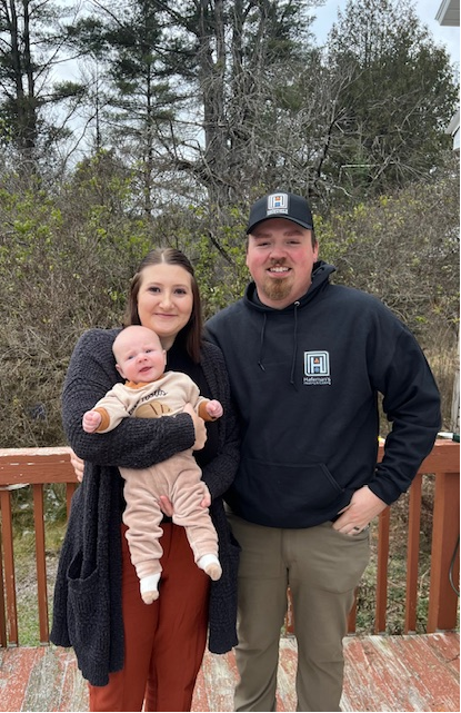 A man and a woman are holding a baby and posing for a picture.