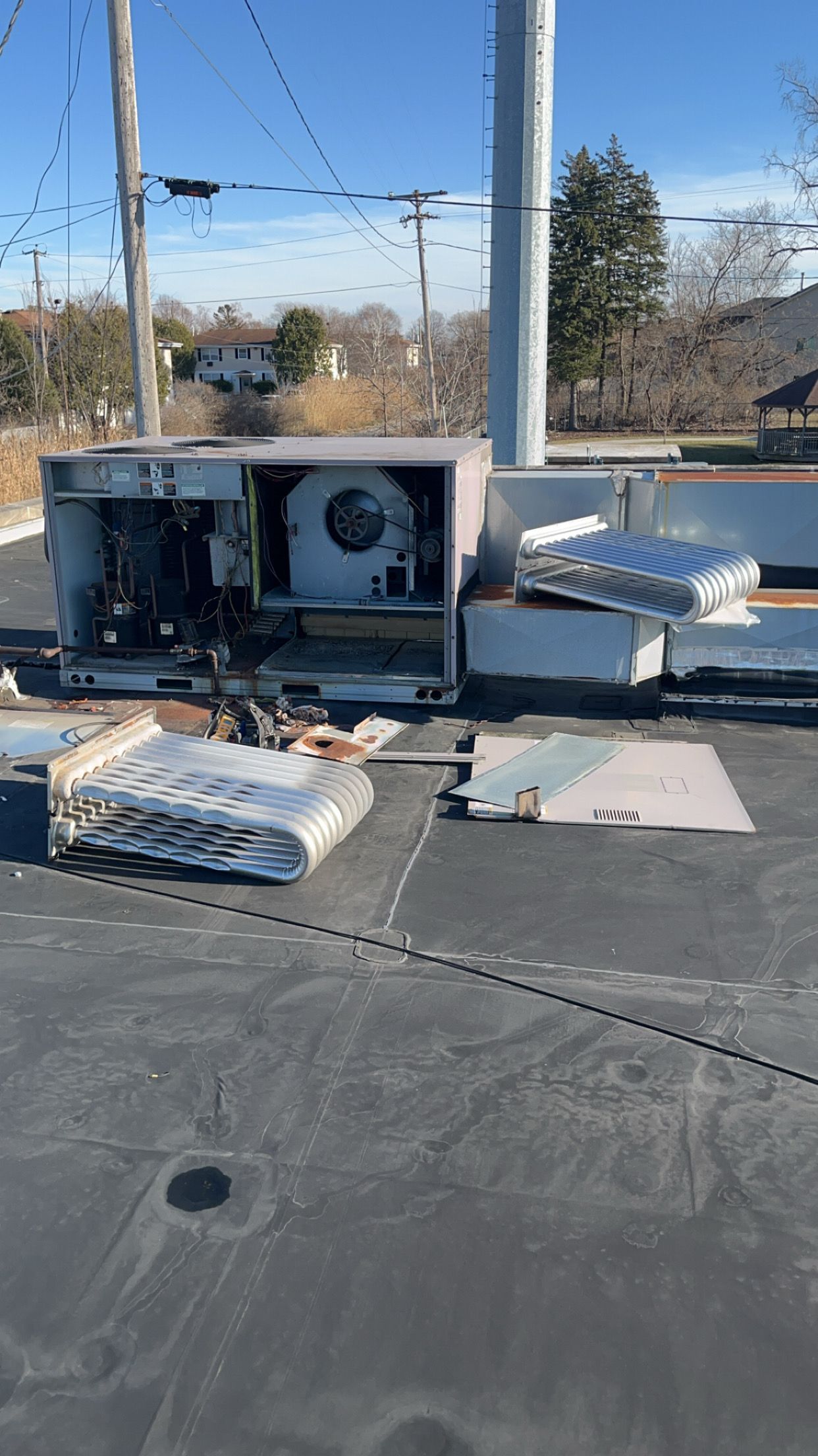 A broken air conditioner is sitting on top of a roof.