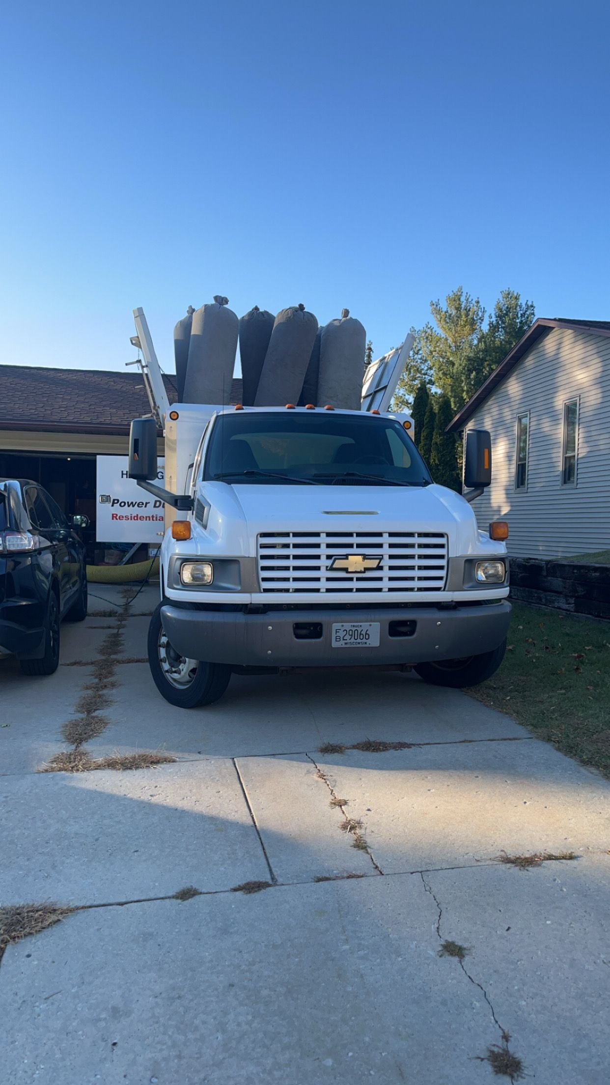A white truck is parked in a driveway next to a house.