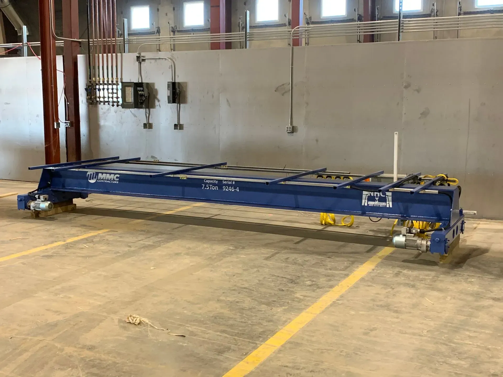 Blue industrial machine or conveyor on a warehouse floor inside a large empty building.