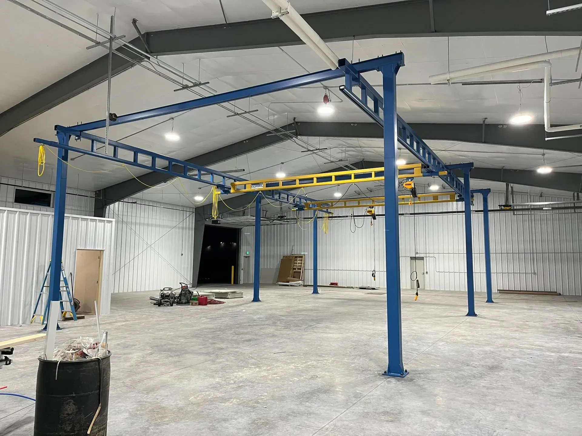 Empty industrial interior with blue steel frame structure and unfinished concrete floor.