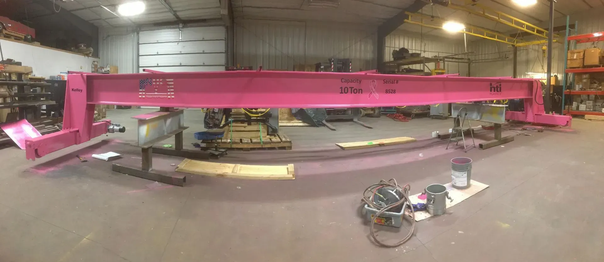 Large pink industrial beam in a warehouse workshop floor with equipment around it.