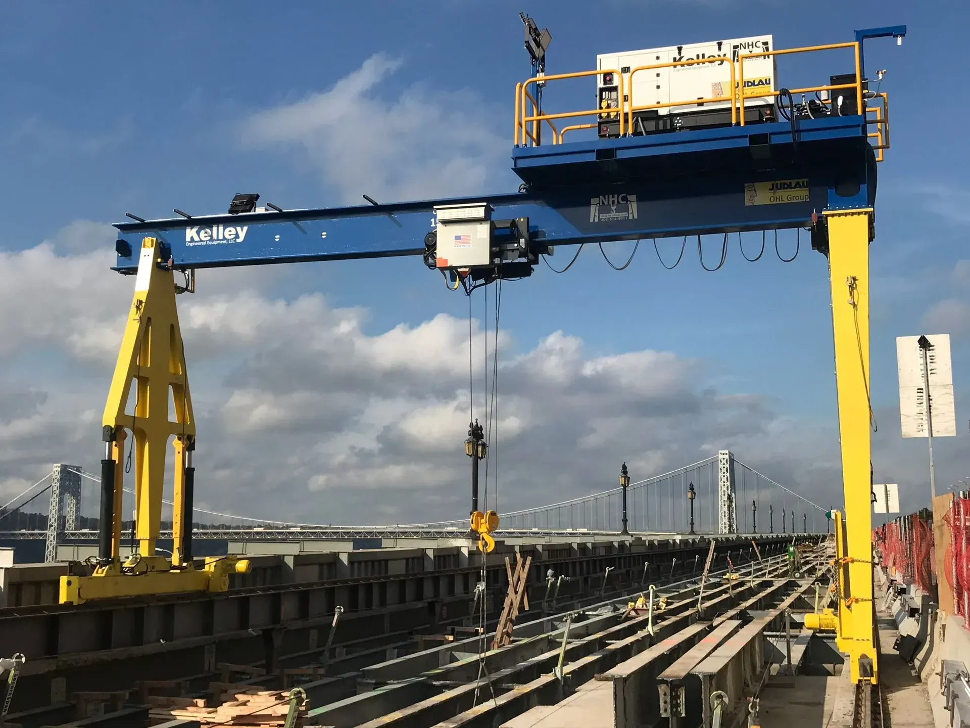 Large yellow gantry crane over a shipyard dock with cables and cloudy sky.
