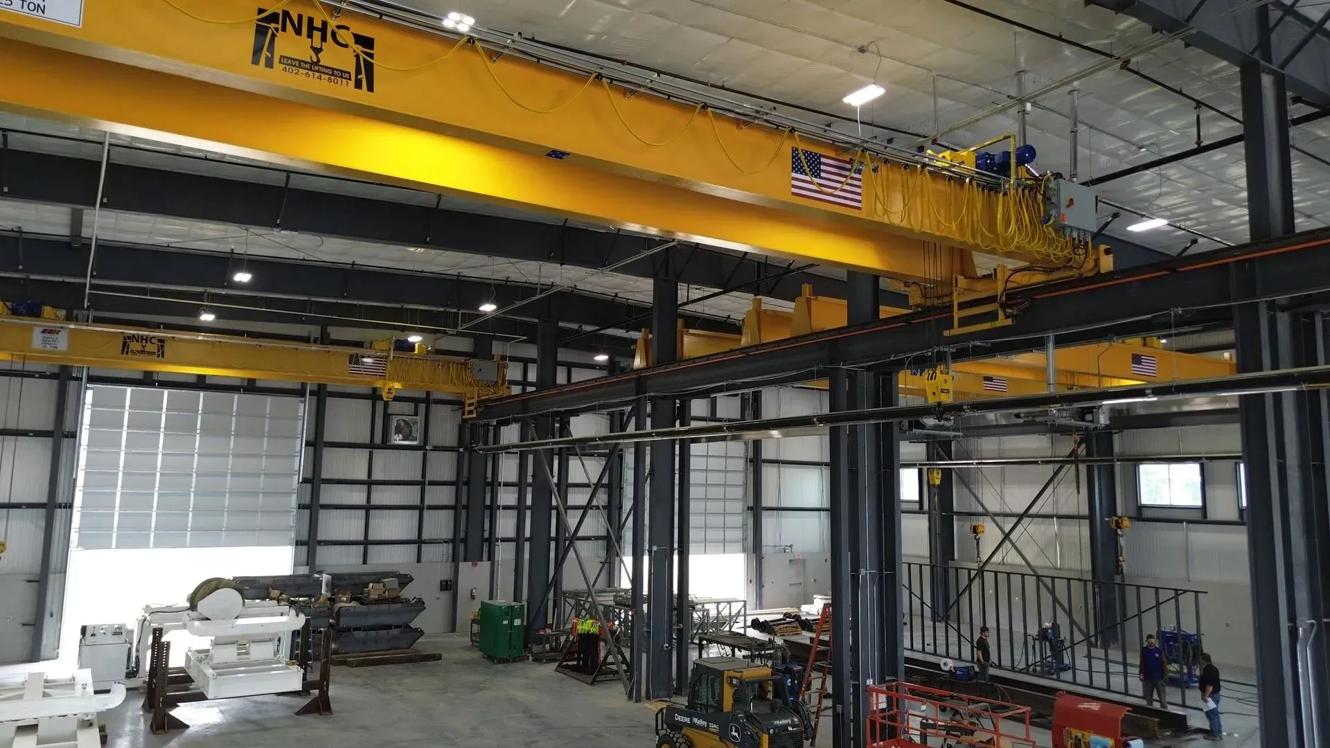 Industrial workshop with yellow overhead crane, steel framework, and machinery under construction.