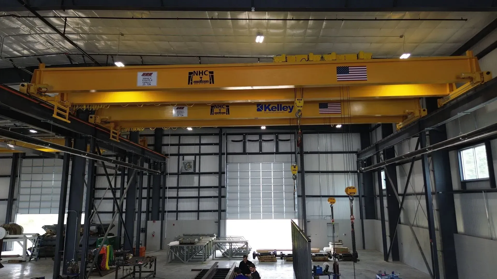 Industrial workshop with a yellow overhead crane inside a metal-framed building under construction.