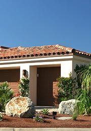 A house with a tiled roof and a large rock in front of it.