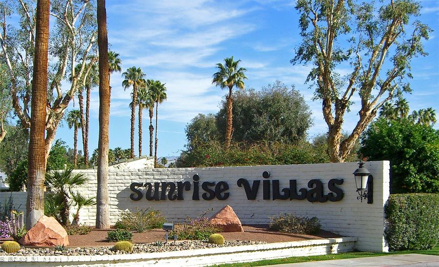 A sign for sunrise villas with palm trees in the background