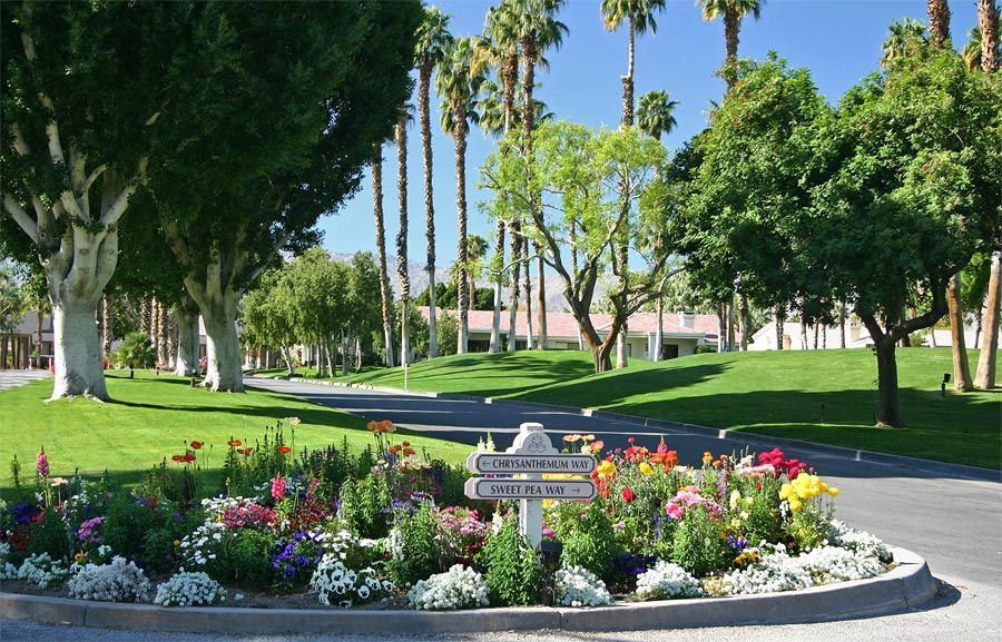 A garden with flowers and a sign that says welcome