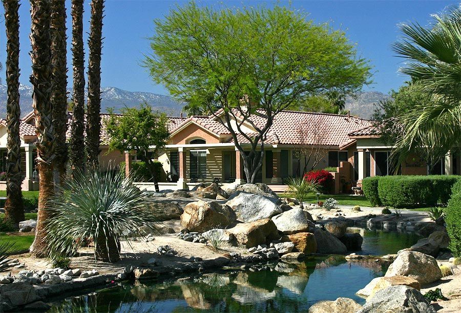 A house with palm trees and a pond in front of it