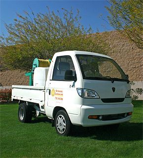 A white truck is parked on a lush green field