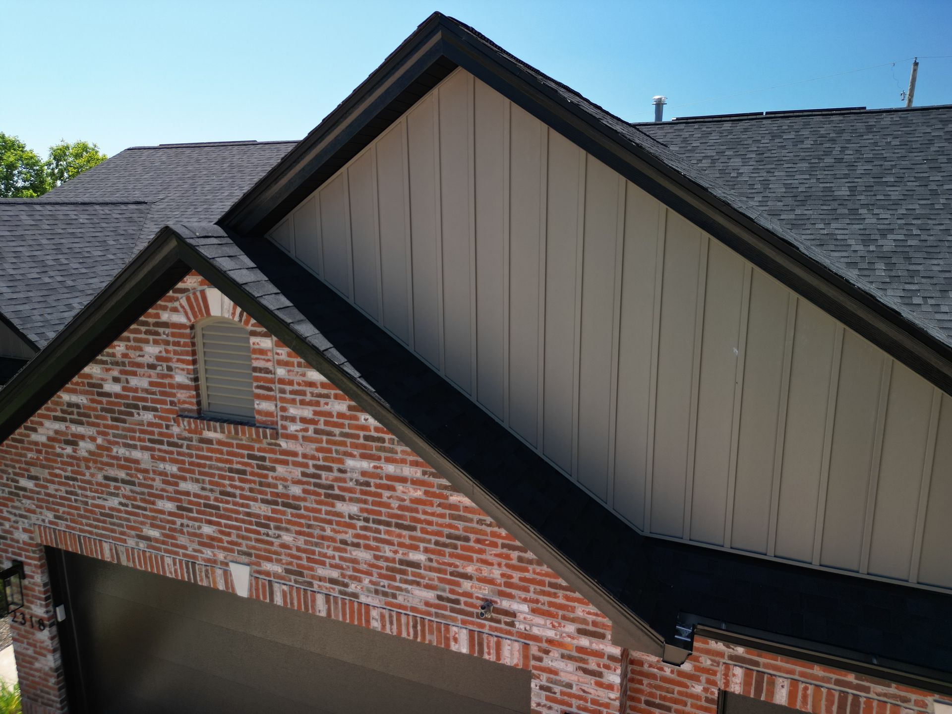 Brick house gables with dark shingled roofs against a clear blue sky