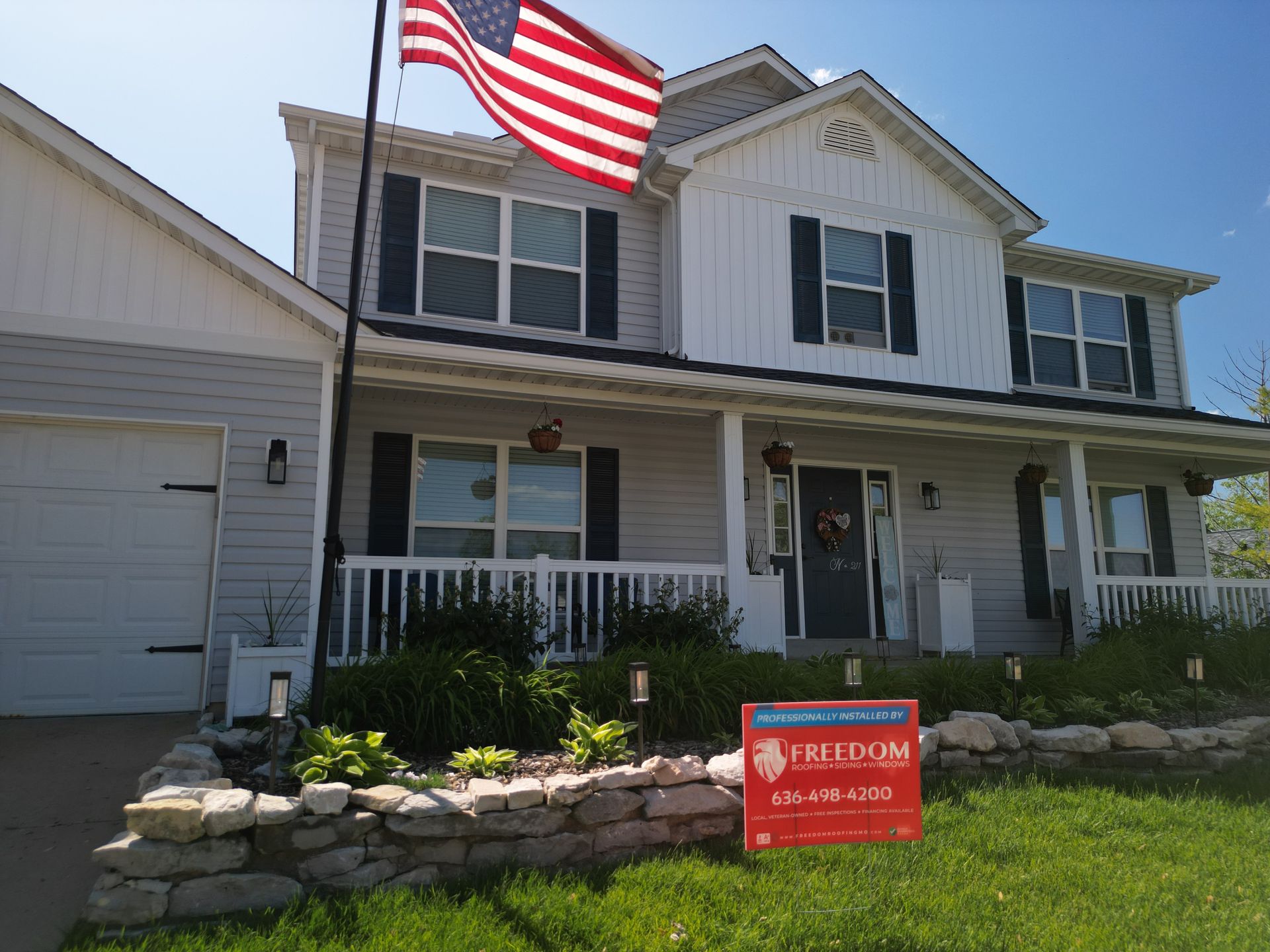 White house with an American flag and a red yard sign in the front yard