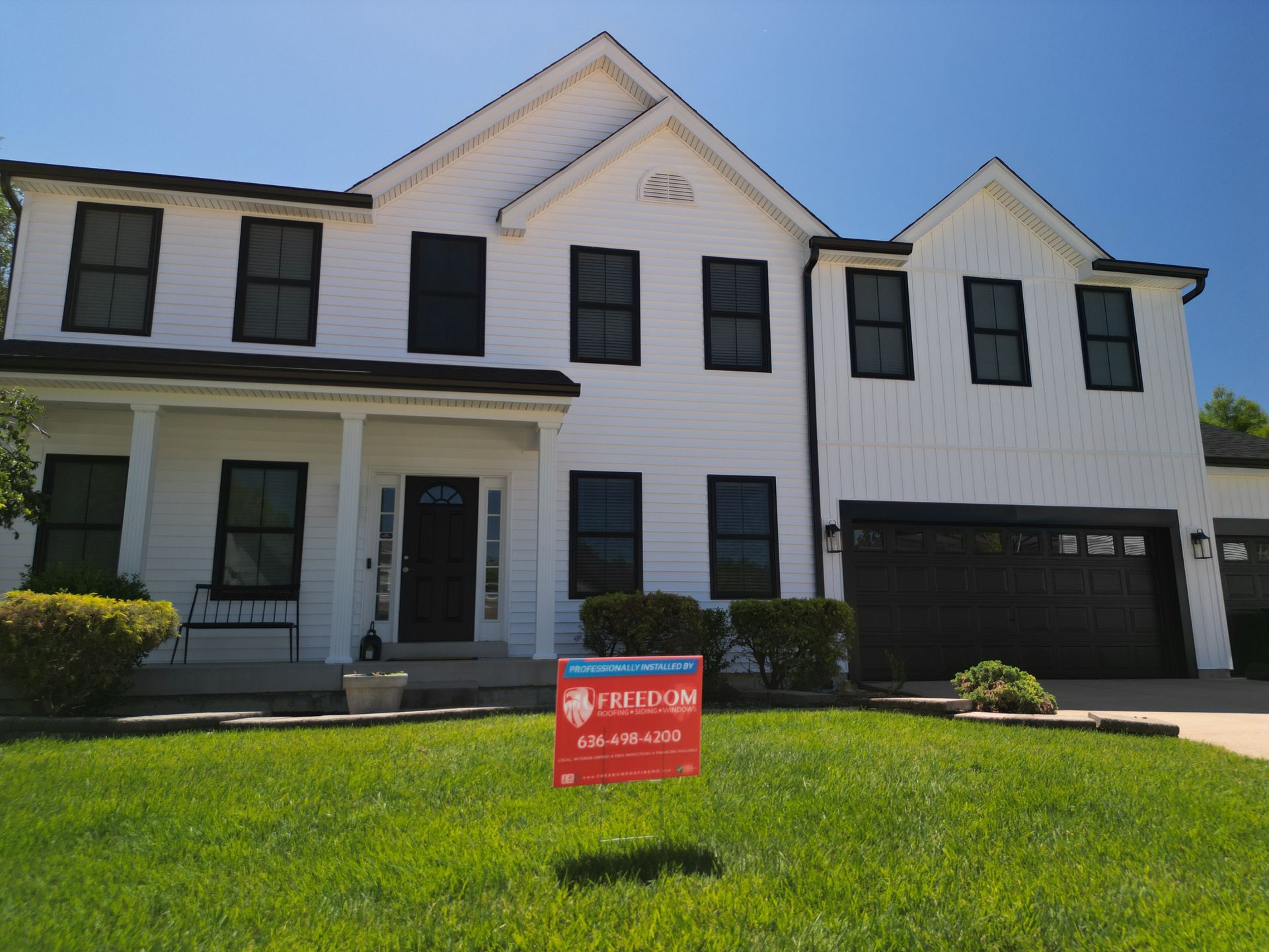 Two-story white house with black shutters and a red real estate sign on the front lawn