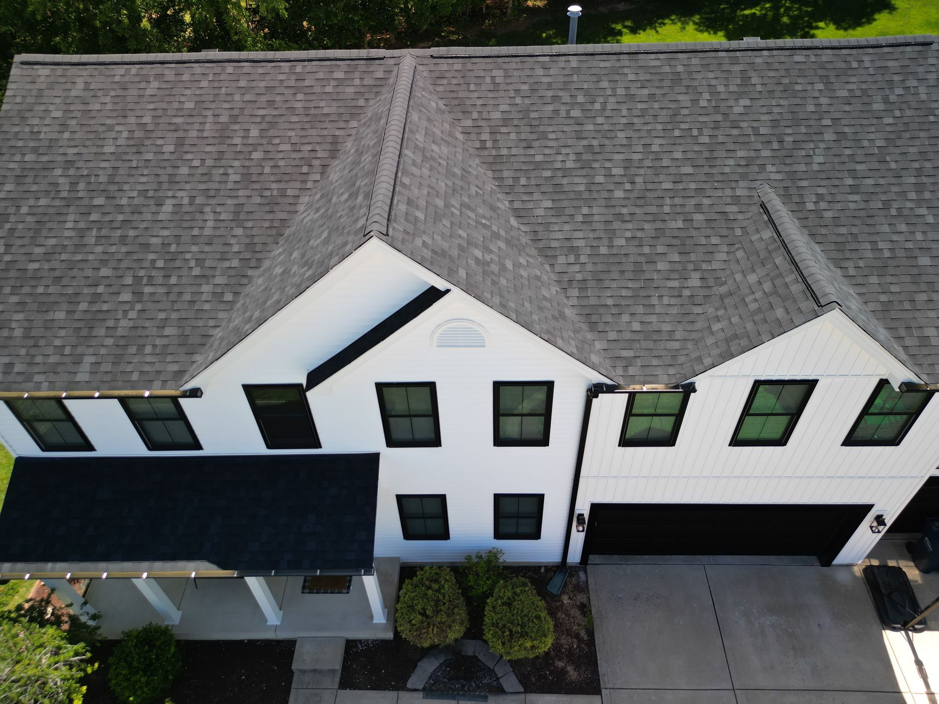 Aerial view of a white townhouse roof with black shutters and a dark front porch overhang