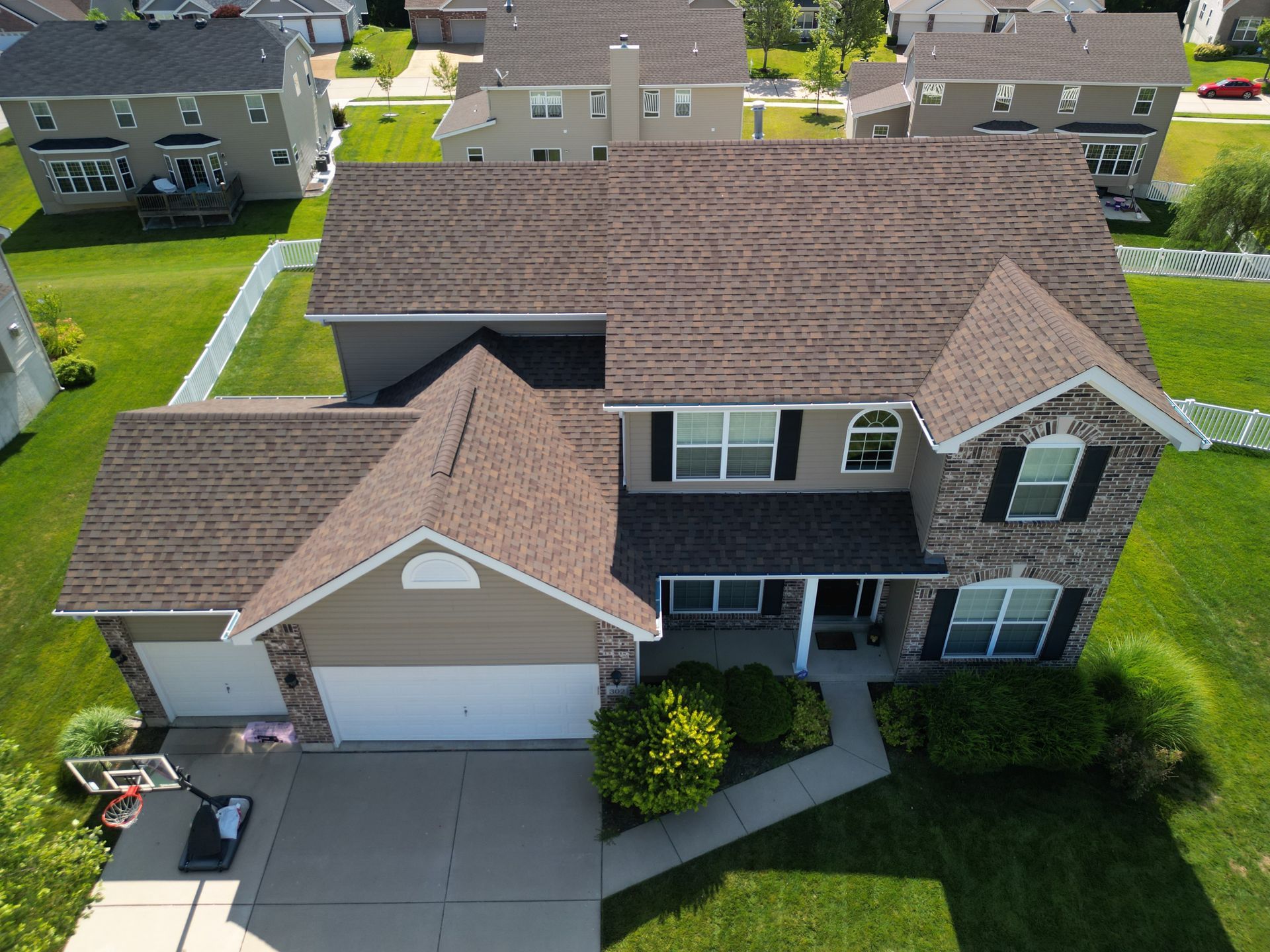 Aerial view of a two-story suburban house with a two-car garage and front lawn.