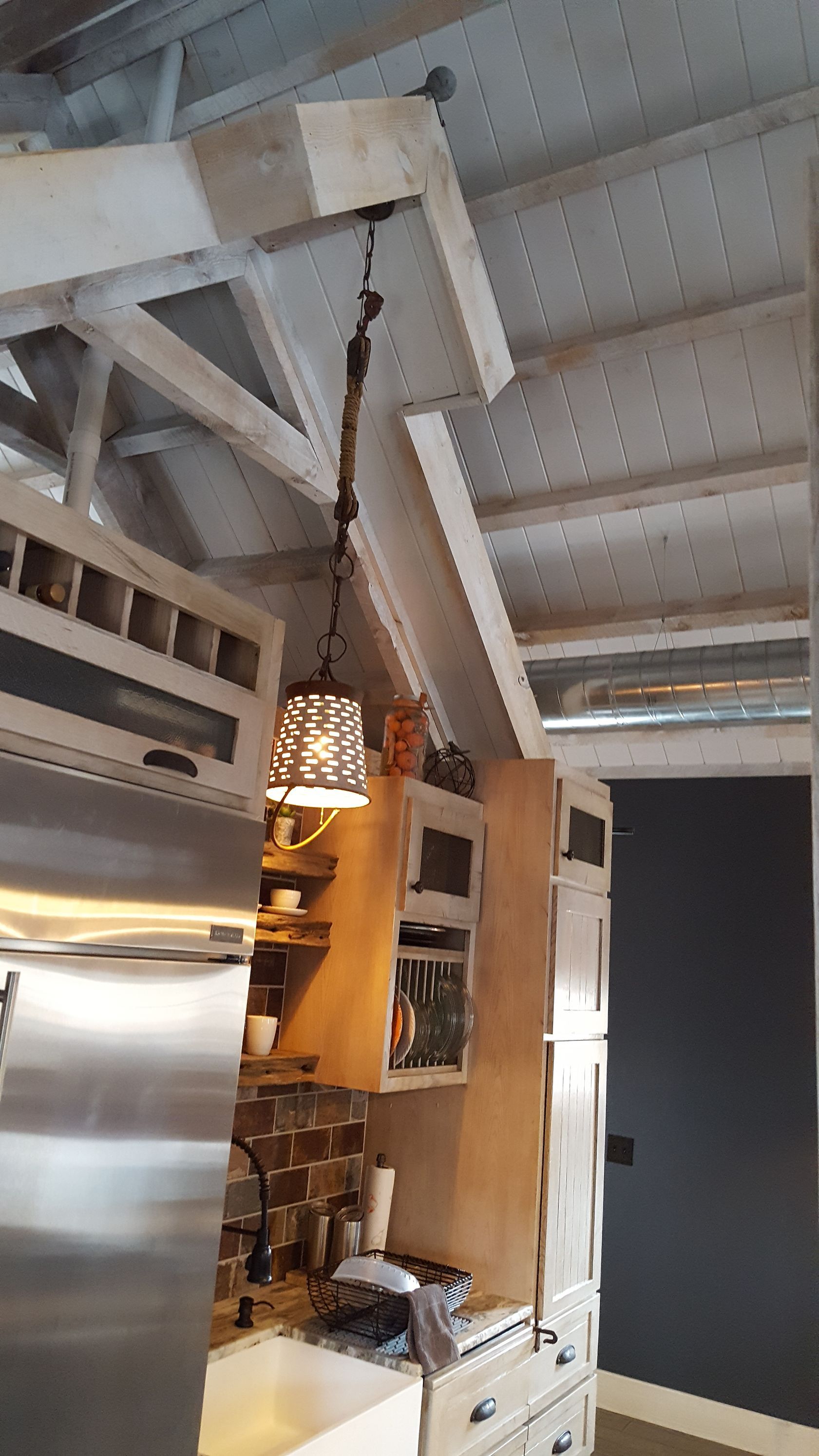 A kitchen with stainless steel appliances and a pendant light hanging from the ceiling.