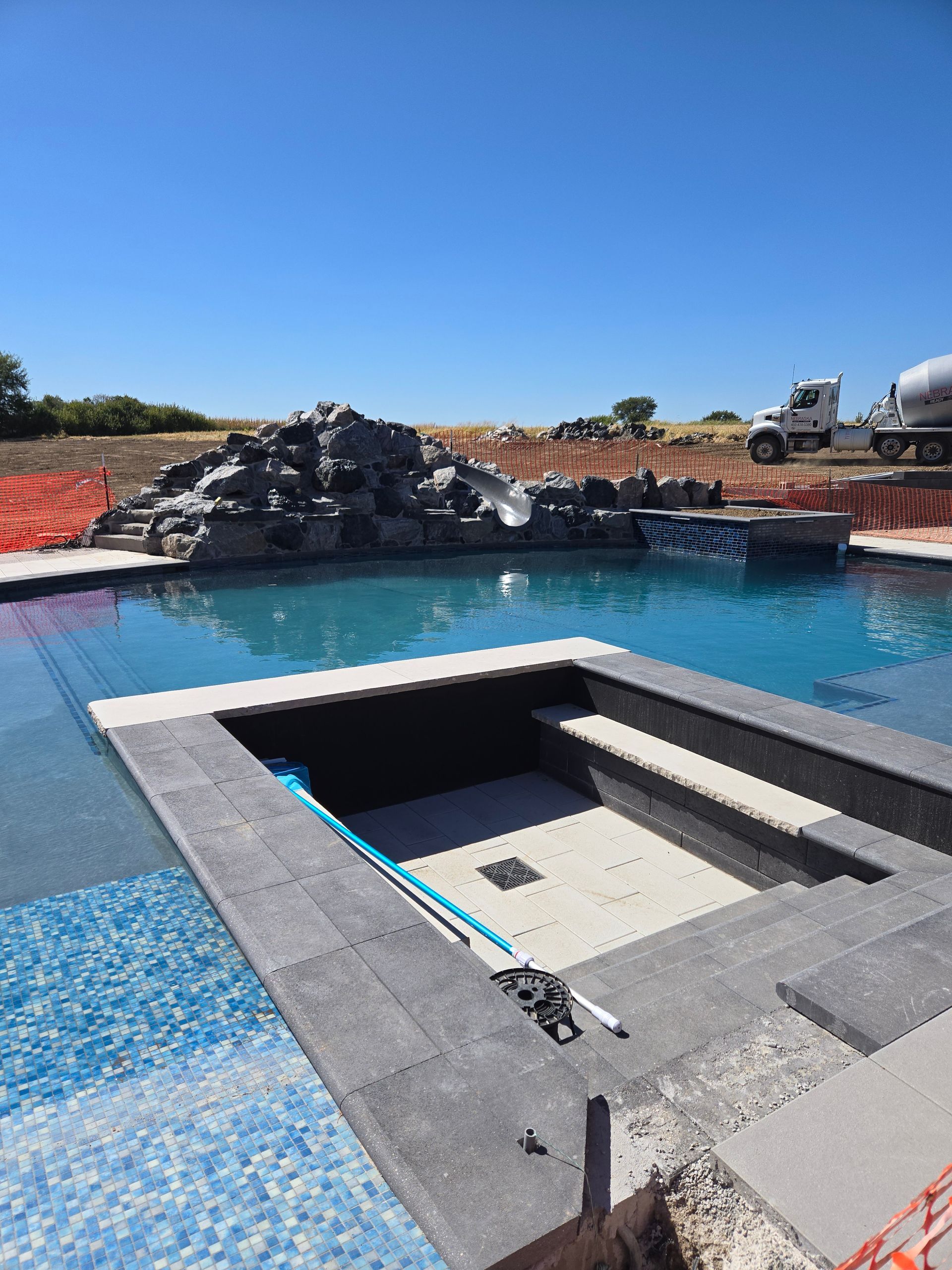 A large swimming pool is being built with a truck in the background.