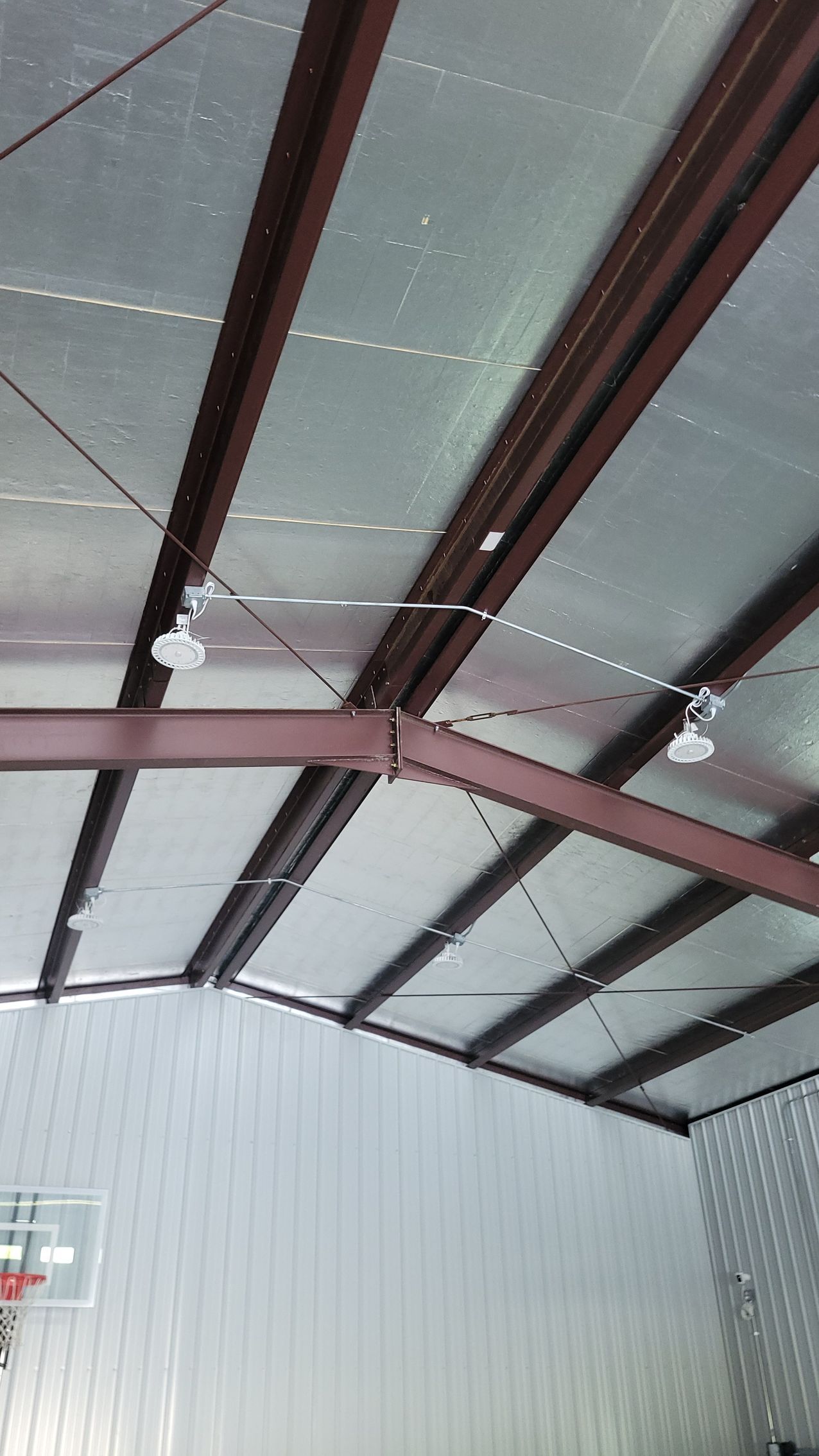 The ceiling of a building with a basketball hoop in the background.