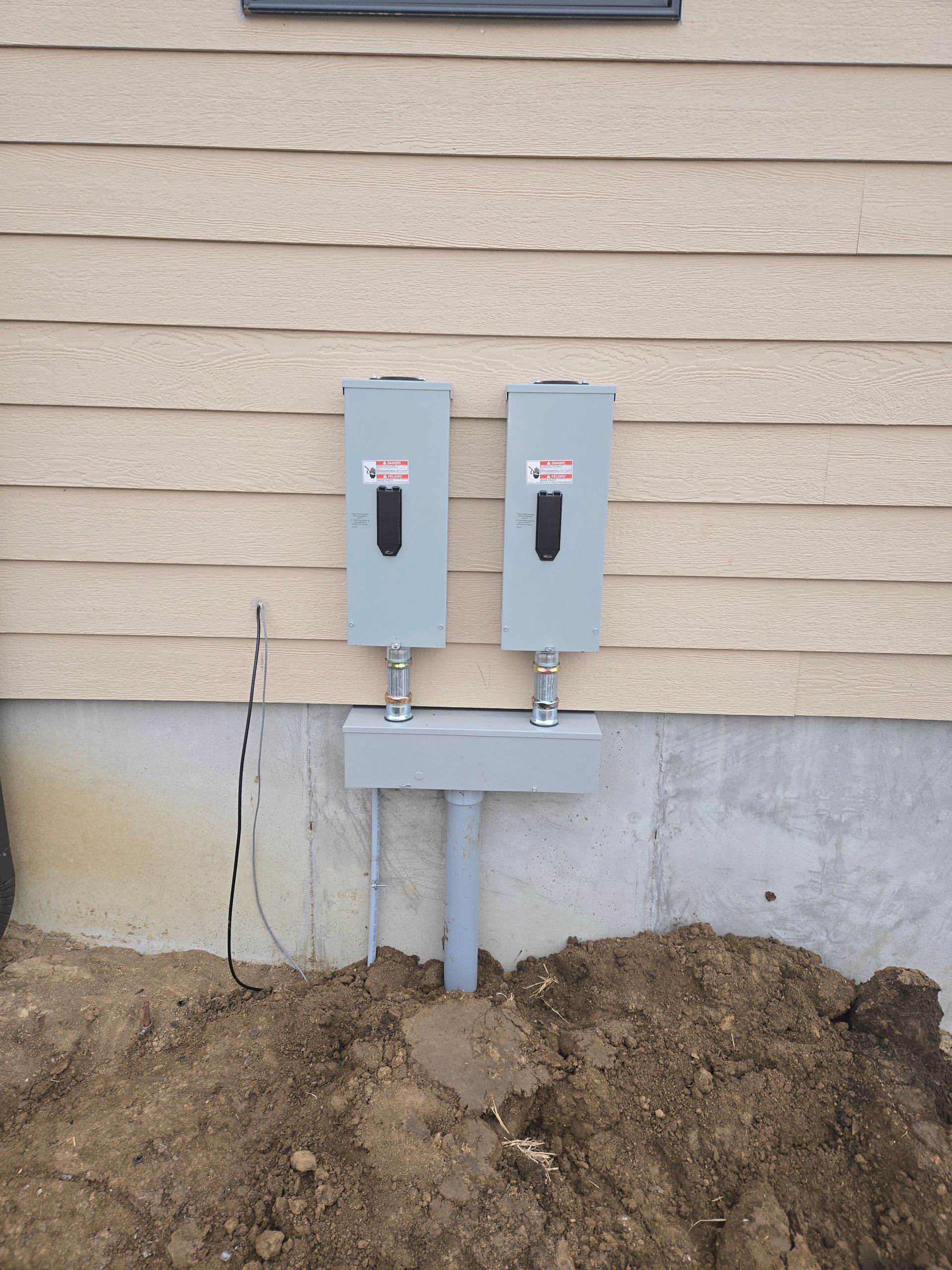 A couple of electrical boxes on the side of a house.