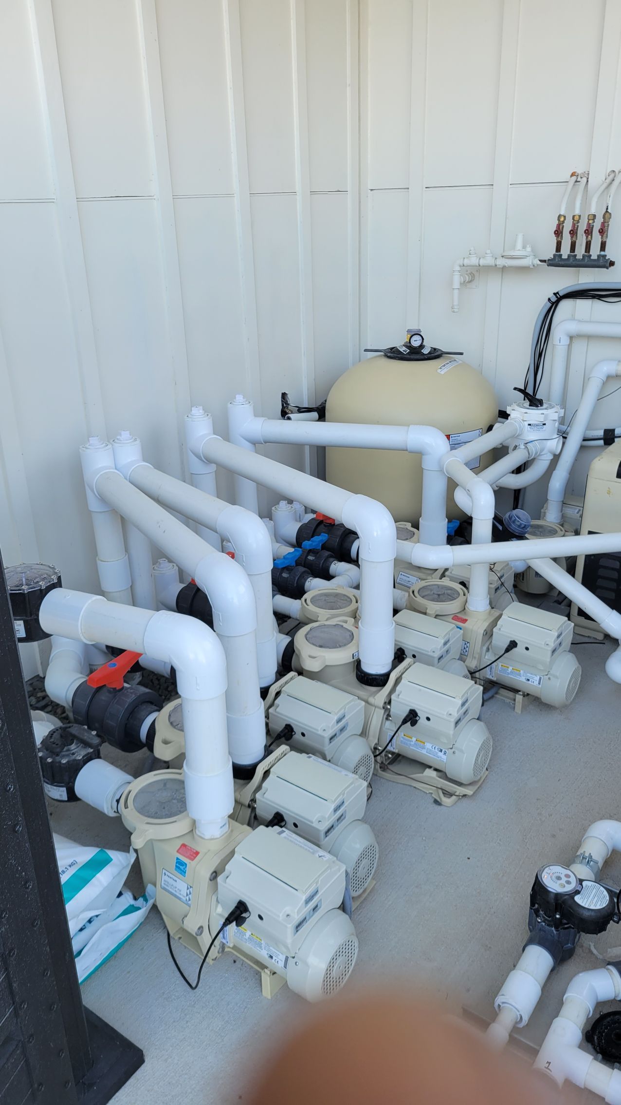 A room filled with lots of pipes and pumps for a swimming pool.
