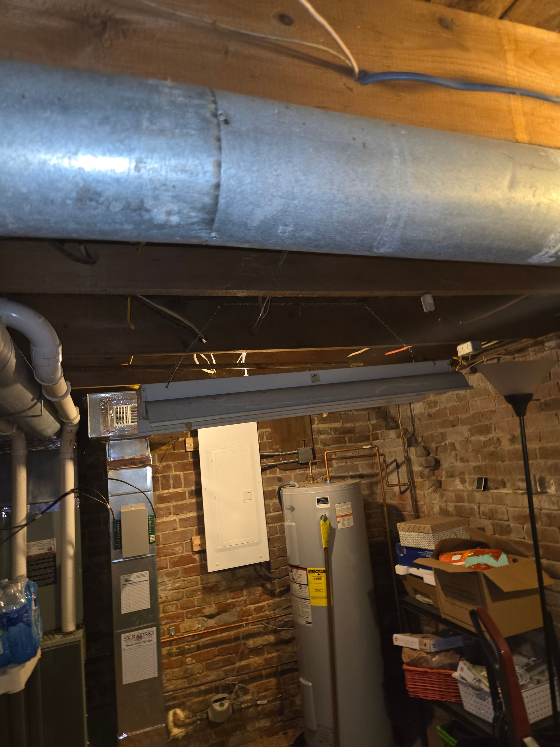 A metal pipe is hanging from the ceiling of a basement.