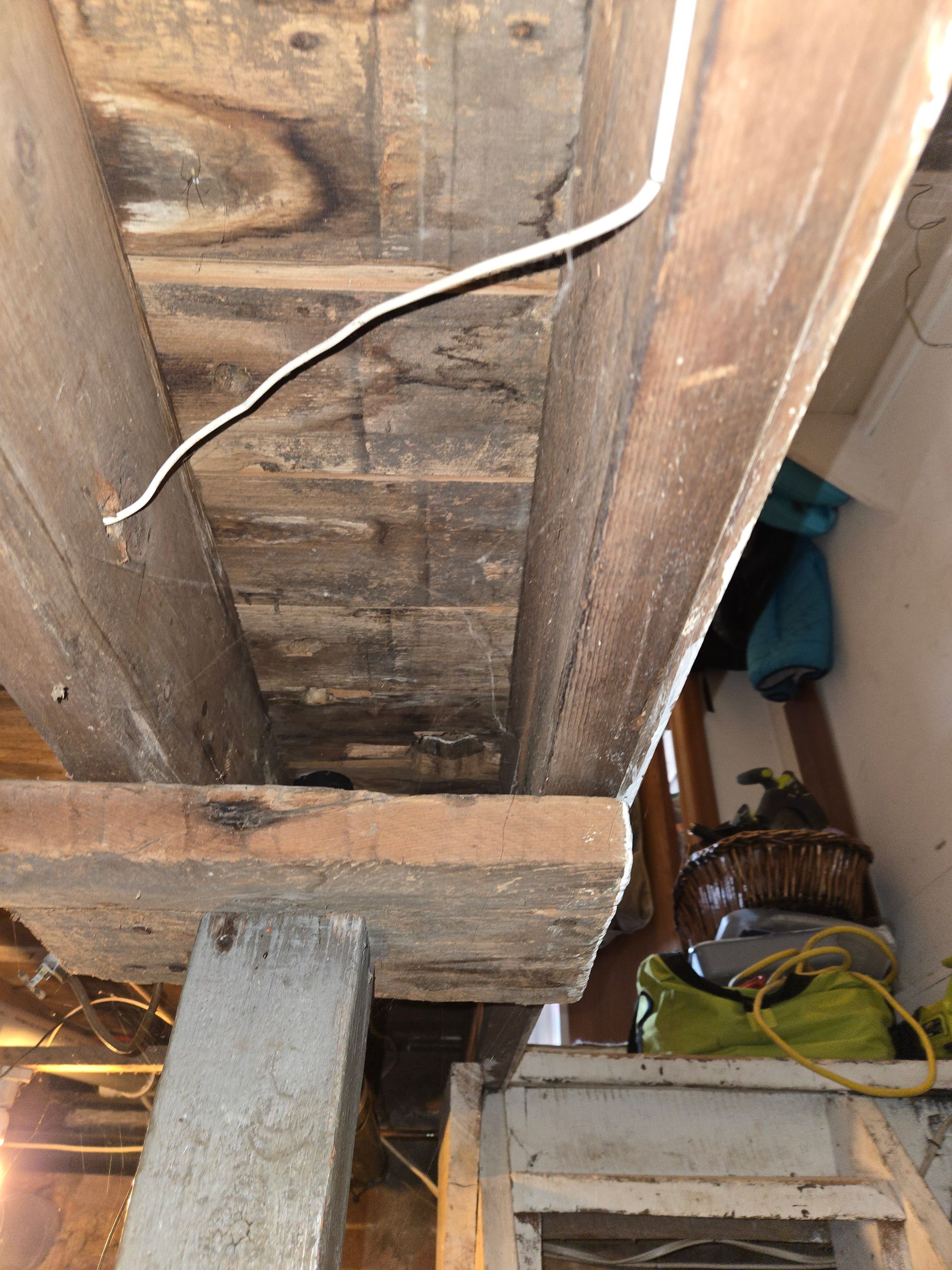 A ladder is sitting under a wooden beam in a room.