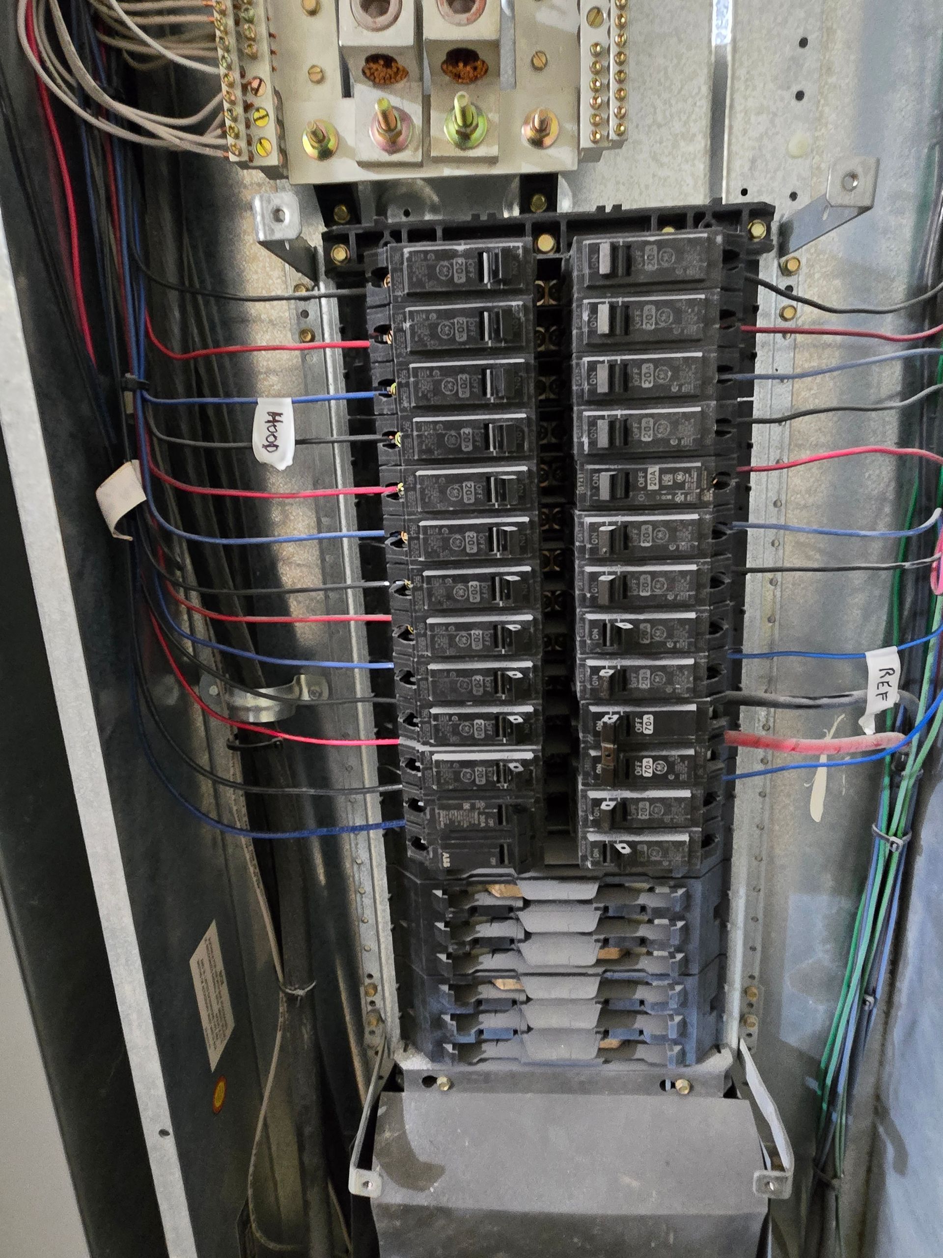 A close up of a electrical panel with a lot of wires coming out of it.