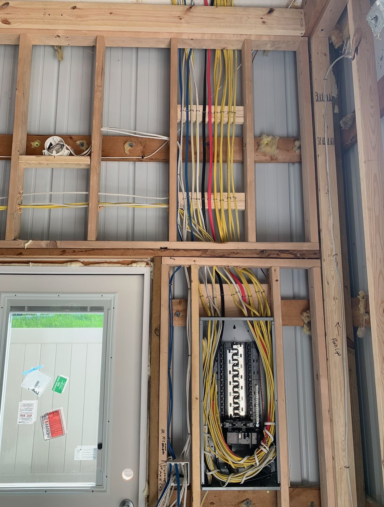 A wall with electrical wires coming out of it and a box.