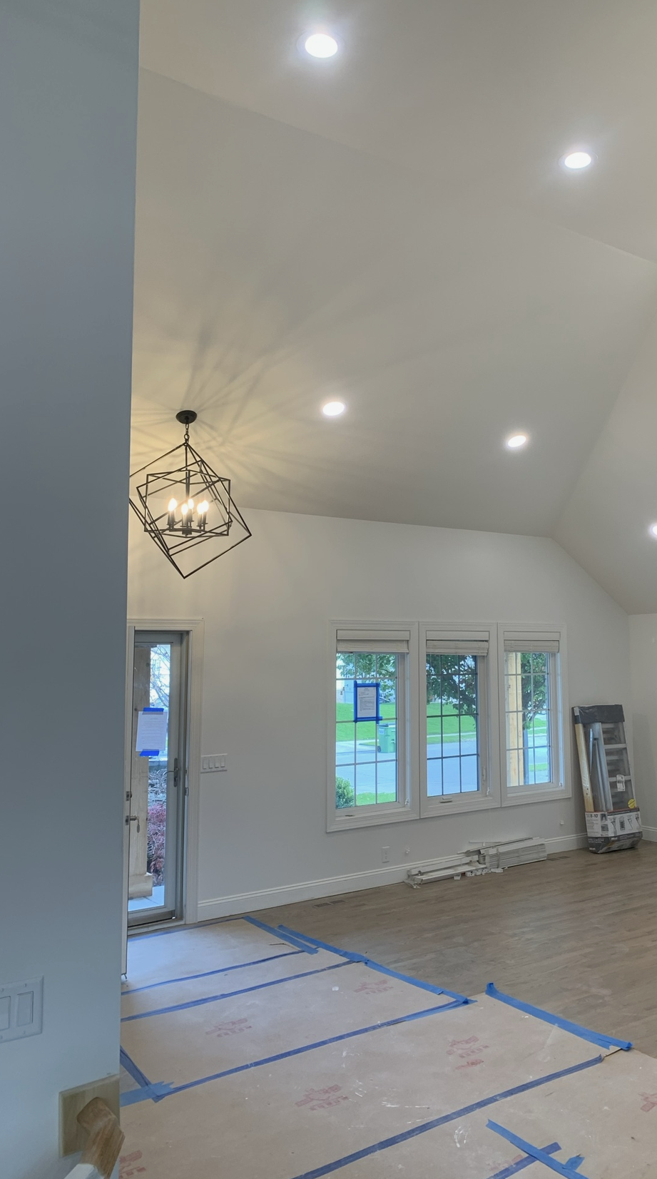 A living room with a chandelier hanging from the ceiling and a lot of windows.