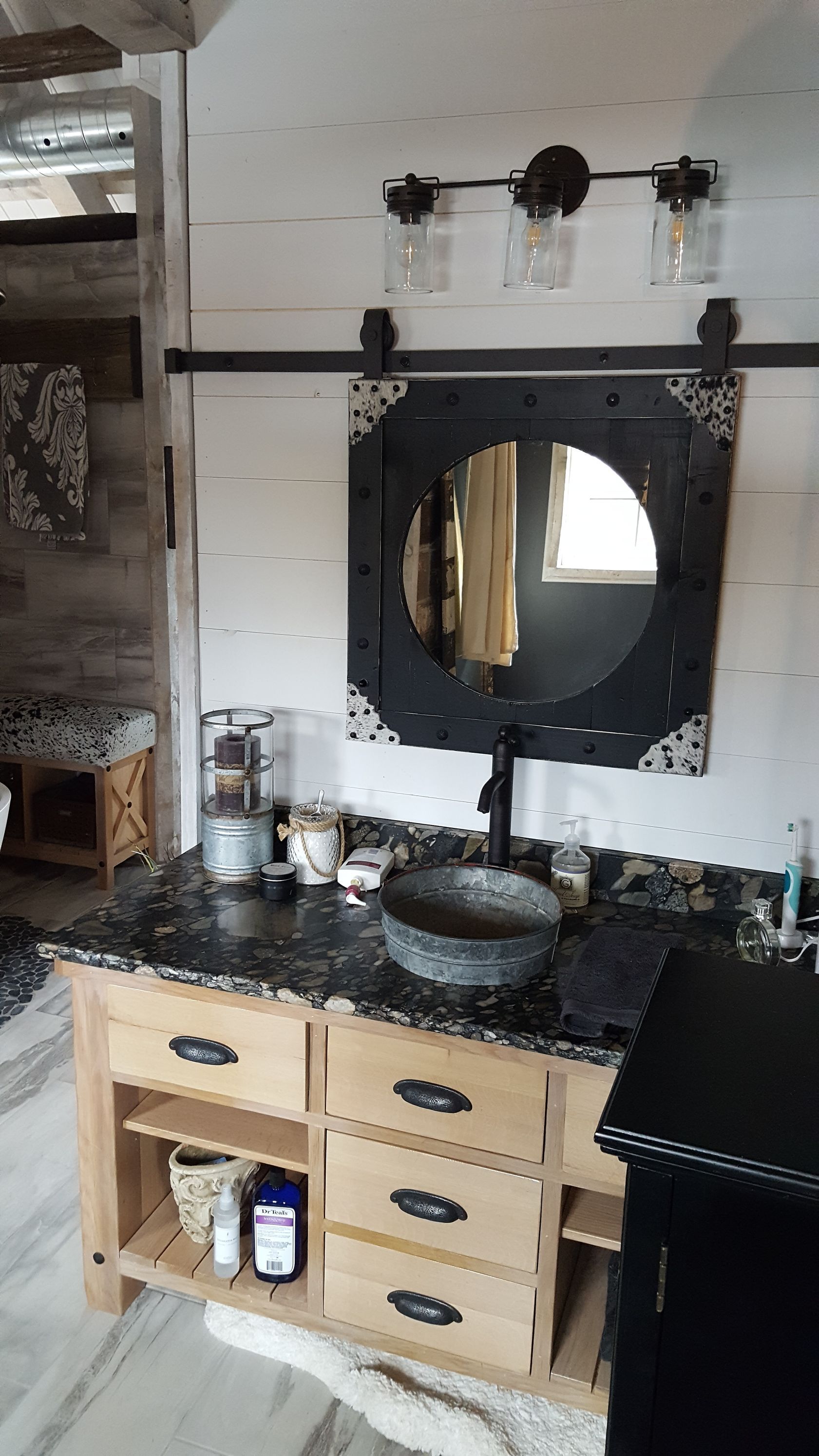 A bathroom with a sink , mirror and drawers.