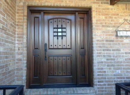 Dark wooden front door with decorative glass, set in a brick house entryway