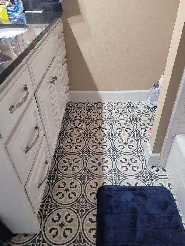Bathroom with white vanity, patterned tile floor, and a dark blue bath mat.