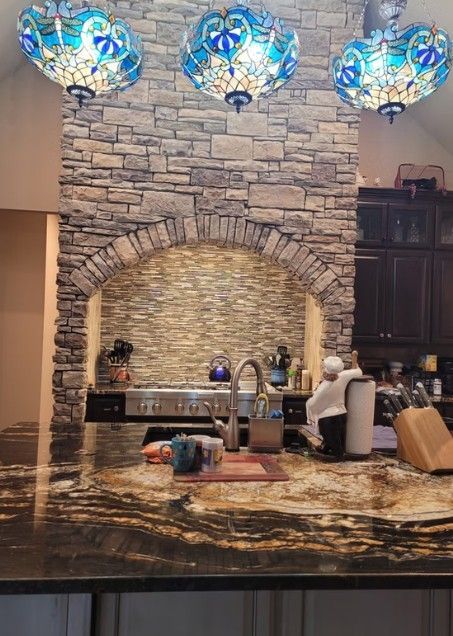Stone fireplace wall with blue glass pendant lights above a polished kitchen island